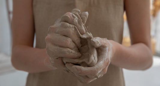 person holding and squishing a ball of wet clay in their hands