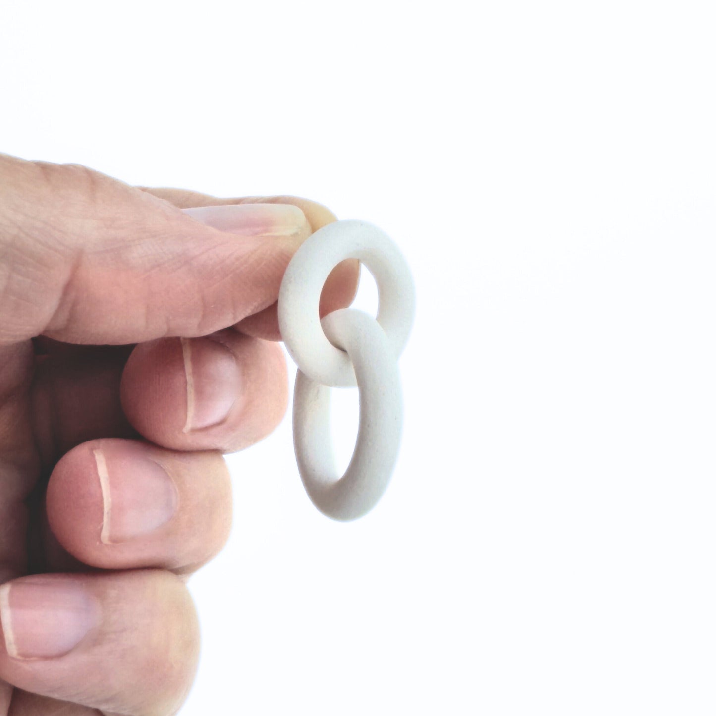 Hand holding a white silicone ring against a white background
