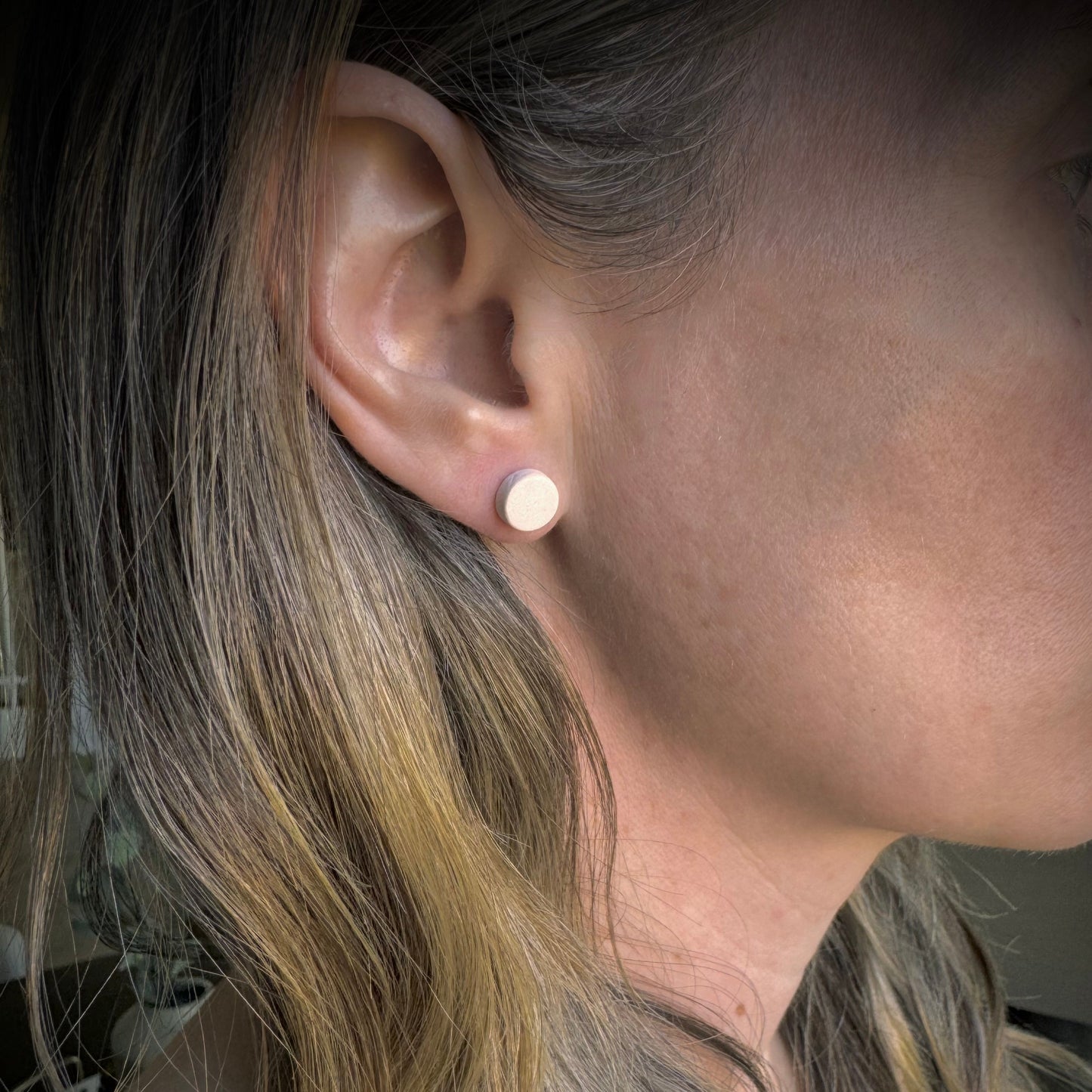Close-up of a person wearing a small round earring.