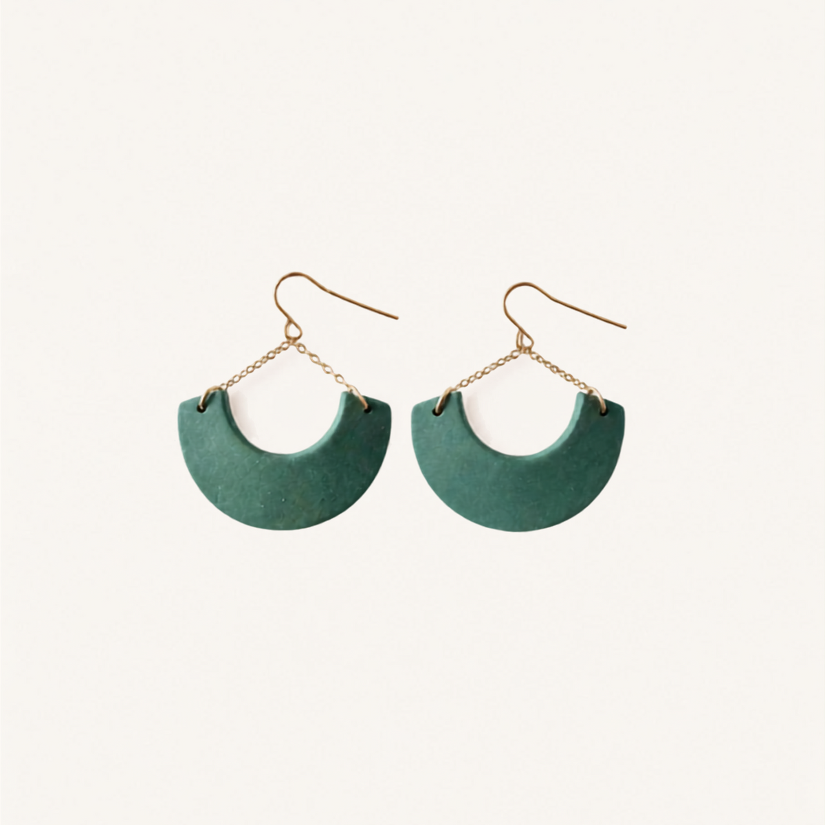 A pair of semi-circular drop earrings with a matte teal green body and gold-tone fishhook wires and chain links, displayed on a clean off-white background.