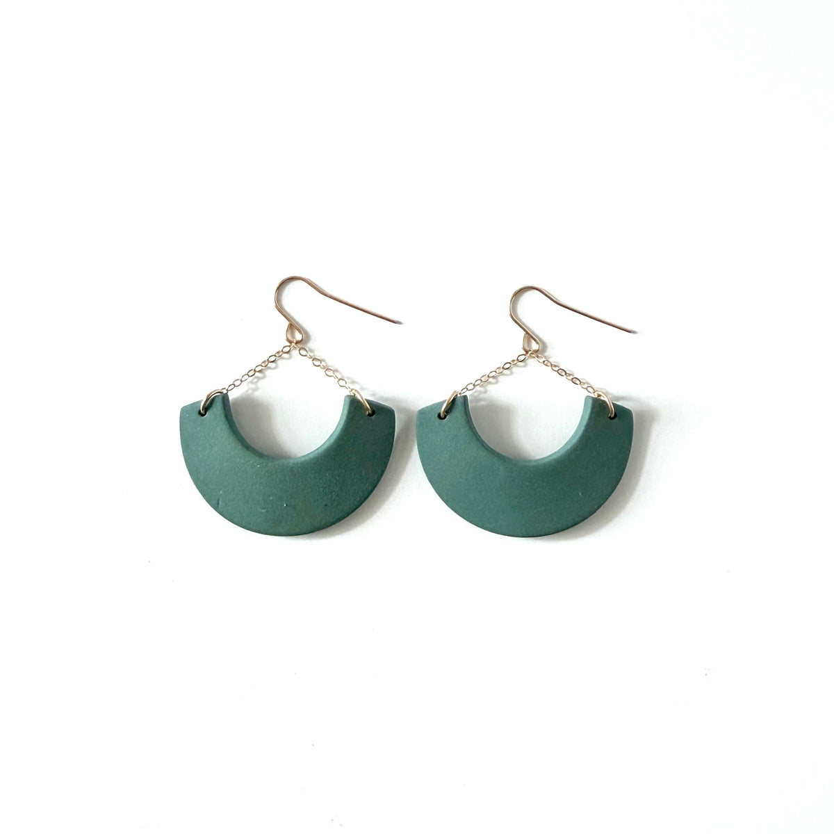 A pair of dangle earrings featuring matte dark green semi-circular shapes suspended from thin 14k gold fill chains and fishhook backings, set against a plain white background.